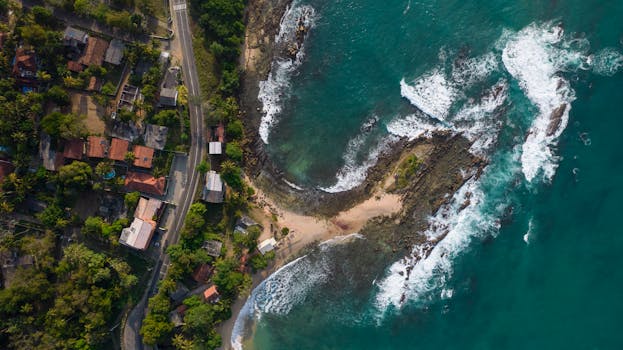 pexels-photo-16508232-16508232 Stunning aerial view of Thangalla coastline with lush greenery and azure ocean waves.